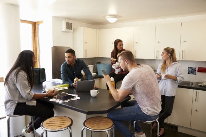 A group of people conversing in a shared kichen.