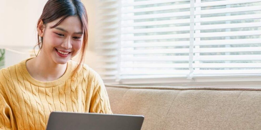 A female sitting on couch and looking at her laptop.