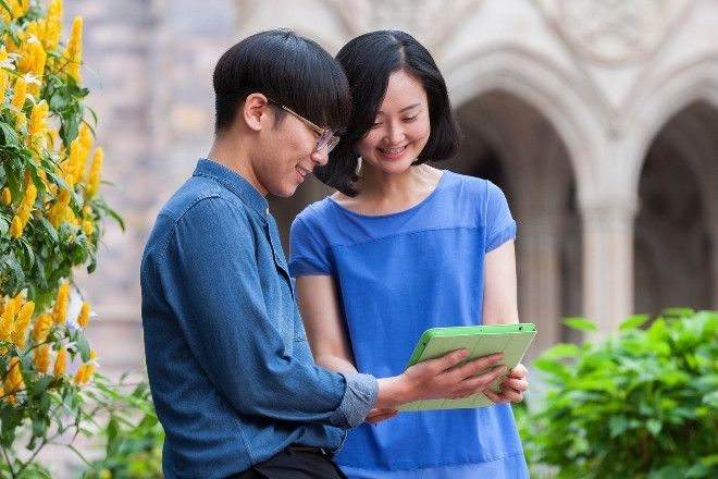 A male and female are sharing an iPad.