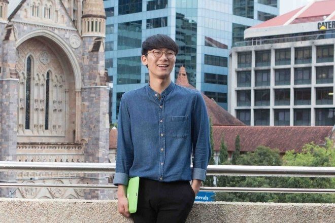 A male students standing on outdoor rooftop.