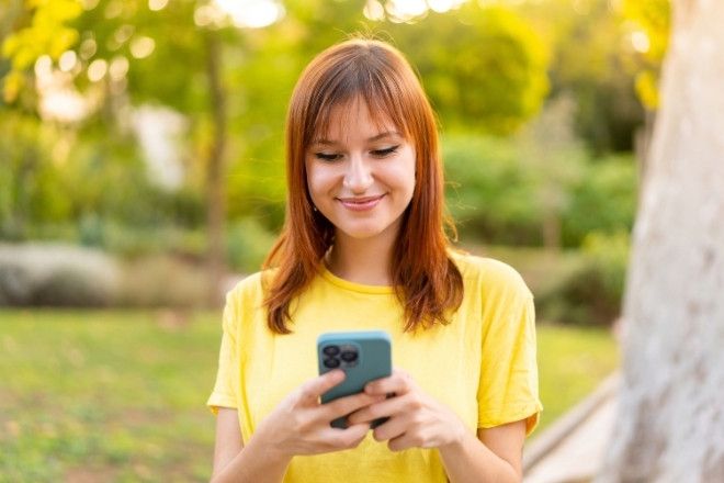 A women looking down at her cellular phone.